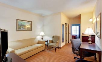 a living room with a couch , chair , and lamps is shown next to a desk and doorway at Country Inn & Suites by Radisson, Salisbury, MD