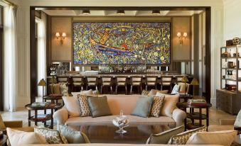 a luxurious living room with a large abstract painting on the wall , surrounded by couches and chairs at The St. Regis Bahia Beach Resort, Puerto Rico