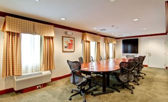 a conference room with a wooden table , chairs , and a television mounted on the wall at Homewood Suites by Hilton Stratford