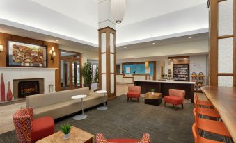 a modern hotel lobby with various seating options , including couches , chairs , and a coffee table at Hilton Garden Inn Stony Brook