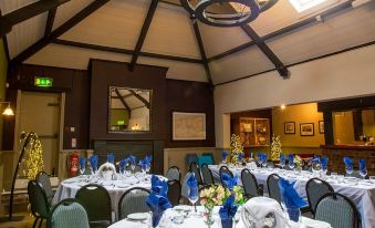 a large dining room with multiple round tables covered in white tablecloths and adorned with blue napkins at The Howard Arms