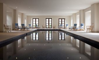 a large , empty indoor pool with multiple rows of lounge chairs and windows in the background at Ballyfin Demesne