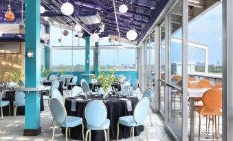 a large , round table with blue chairs is set up in a room with a purple ceiling at The Moonrise Hotel