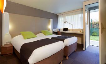 a modern hotel room with two beds , a desk , and a window , giving it a clean and professional appearance at Campanile Villejust - ZA Courtaboeuf