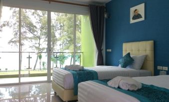 a modern hotel room with two beds , white bedding , and large windows offering views of the ocean at Greenseaviewresort Bangsaphan