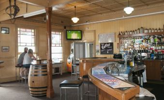 a bar with a wooden interior , including a bar counter and several chairs , as well as a television mounted on the wall at Ulmarra Hotel