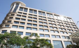 a modern , white building with multiple floors and a large glass window , surrounded by trees and clear blue skies at Courtyard Ahmedabad