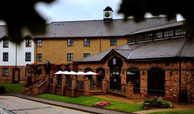 a brick building with a clock tower and an umbrella stand in front of it at Village Hotel Liverpool