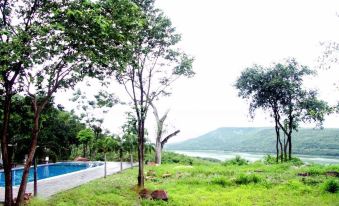 a grassy field with trees and a pool , providing a serene and picturesque setting for relaxation at Suan Muang Porn