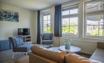 a cozy living room with a couch , chairs , and a tv . also a dining table in the room at EuroParcs de Rijp