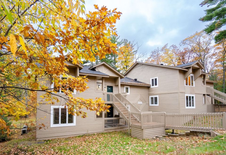 a large house with a staircase leading up to it , surrounded by trees and bushes at Telemark Northwoods Lodging