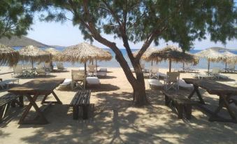 a sandy beach with several tables and chairs , as well as umbrellas providing shade for the area at Victoria Limnos