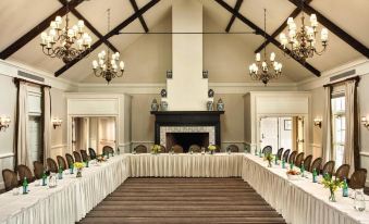 a large dining room with a long table set for a formal event , surrounded by chairs and chandeliers at Inn at Perry Cabin