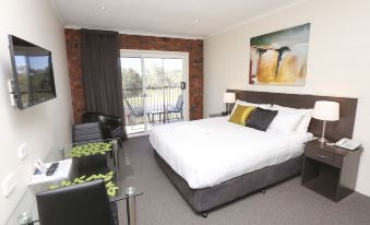 a spacious bedroom with a large bed , a television , and a door leading to a balcony at Mildura Riverview Motel
