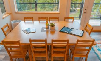 a dining table with chairs , a vase of flowers , and a bottle of wine on it at Woodland Cabins