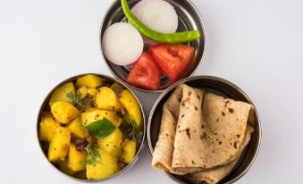a table with three bowls containing various food items , including naan bread and tomato at Collection O 27949 Hotel Kriti Green