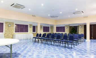 a large , empty conference room with rows of blue chairs and yellow walls , set against a backdrop of a white ceiling at Infinity on the Beach