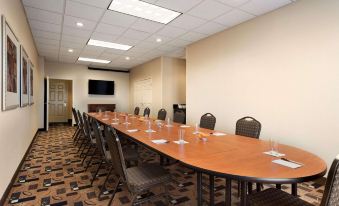 a large conference room with a long wooden table , several chairs , and a television mounted on the wall at Country Inn & Suites by Radisson, Evansville, IN