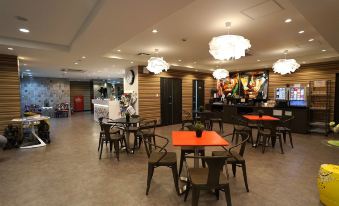 a large restaurant with multiple dining tables and chairs , some of which are covered in orange tablecloths at Hotel 88 Shinsaibashi