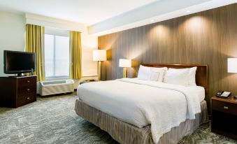 a large bed with white linens and a wooden headboard is in a room with a window at SpringHill Suites Florence