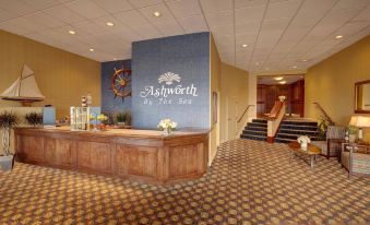 a hotel lobby with a wooden reception desk , carpeted floor , and a staircase leading to the second floor at Ashworth by the Sea