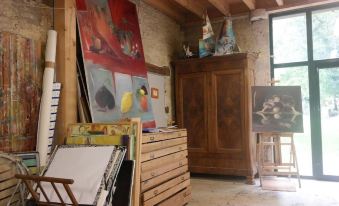 a room with wooden furniture , including a cabinet and a desk , filled with various art supplies and paintings at Le Petit Paris
