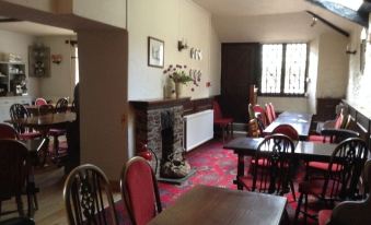 a dining room with wooden tables and chairs , a fireplace , and a window overlooking the city at The Durant Arms
