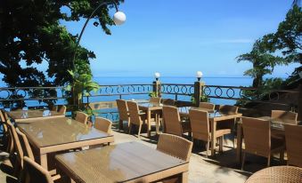 an outdoor dining area overlooking the ocean , with several tables and chairs arranged for guests to enjoy a meal at Top Resort