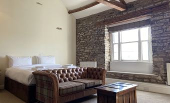 a cozy living room with a brown leather couch and a wooden coffee table in front of a window at The Greyhound Hotel