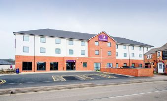 a red brick building with a purple sign and a white facade , located on a street at Premier Inn Melton Mowbray