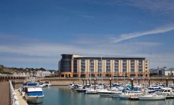 a large building is situated next to a marina filled with boats and boats docked in the water at Radisson Blu Waterfront Hotel, Jersey