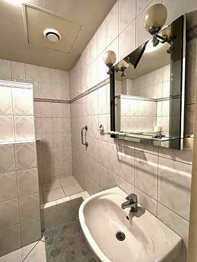 a bathroom with white tiled walls , a mirror above the sink , and a shower area at Titanic