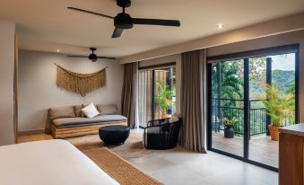 a modern bedroom with a bed , couch , and sliding glass doors leading to an outdoor patio at Punta Islita, Autograph Collection