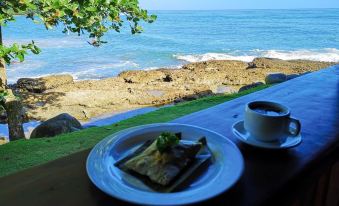 a plate of food is placed on a table with a cup of coffee in front of it , overlooking the ocean at Hotel Playa Bonita