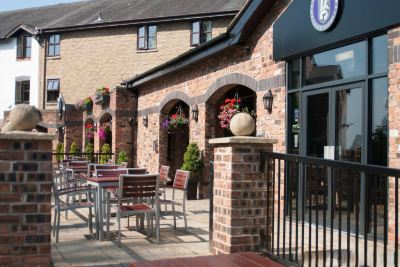 a brick building with a patio area featuring several tables and chairs , as well as a door leading to a storefront at Village Hotel Liverpool