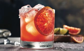 a glass of cocktail with a slice of grapefruit on top , placed on a wooden table at Courtyard Houma