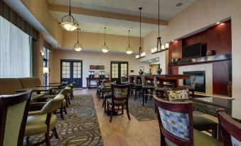 a modern , well - lit dining room with various seating options and a large tv on the wall at Hampton Inn & Suites Denver Littleton