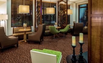 a modern lounge area with brown and green furniture , candles , and a large window with curtains at Hilton Garden Inn Uniontown