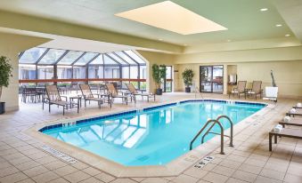 a large indoor swimming pool with a glass ceiling and lounge chairs around it , providing a relaxing atmosphere at Courtyard Chicago Wood Dale / Itasca