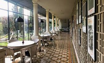 a long , narrow room with white columns and a tiled floor is adorned with tables and chairs at La Maison Navarre