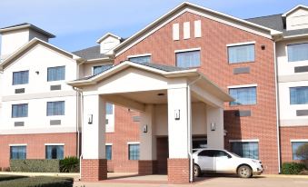 "a red brick hotel with a white car parked in front and a sign reading "" south loop "" on the sidewalk" at Franklin Inn and Suites