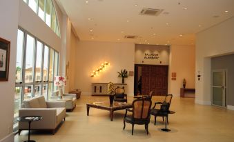 a spacious and well - lit hotel lobby with a reception desk , chairs , couches , and potted plants at Bourbon Cambara Hotel