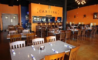 a large restaurant with multiple dining tables and chairs , as well as a bar area at Amelia Extended Stay & Hotel