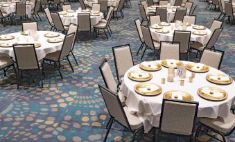 a large banquet hall with multiple round tables and chairs set up for a formal event , possibly a wedding reception at Fun City Resort Hotel