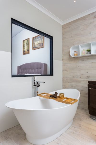 a modern bathroom with a large white bathtub in the middle of the room , surrounded by various items such as bottles , cups , and books at The Swan Valley Retreat