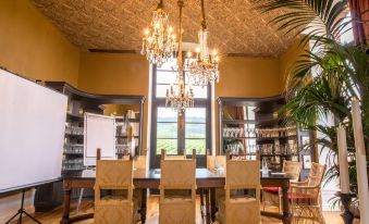 a dining room with a wooden table and chairs , surrounded by bookshelves and large windows at Chateau de Sacy