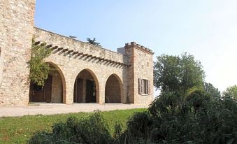 a large stone building with three arched doorways and a grassy lawn in front of it at Villa Luisa
