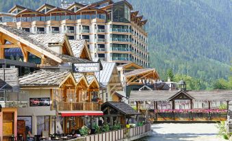 a building with a restaurant on the ground floor , surrounded by trees and mountains in the background at Hotel le Morgane