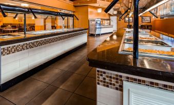 a large restaurant with multiple dining tables and chairs , as well as a kitchen area with various appliances at Best Western State Fair Inn