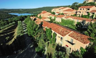 aerial view of a residential area with multiple houses and a lake in the background at Belambra Clubs Montpezat - le Verdon